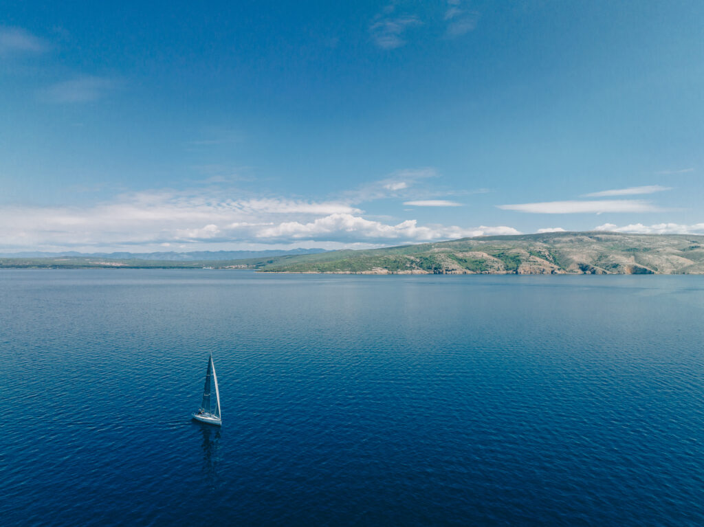 A single sailing yacht in the calm Kvarner Bay off the island of Krk