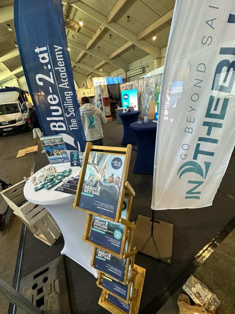 IN2THEBLUE and BLUE-2 exhibition stand at the Boot Tulln boat show with beach flags and brochures