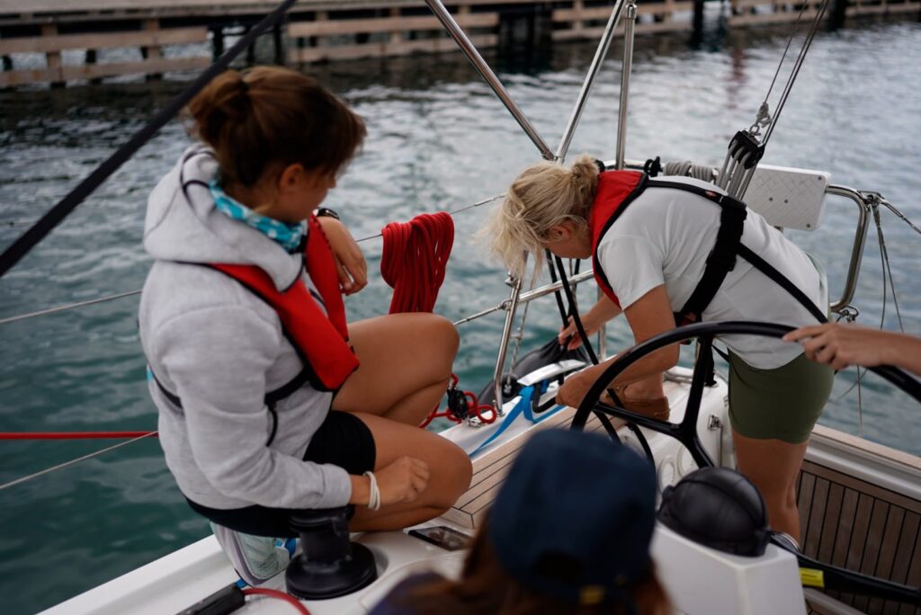 Two women prepare a berthing manoeuvre on deck