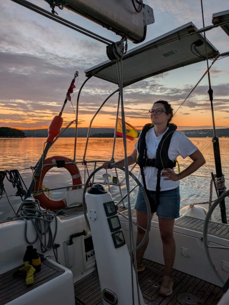 Skipper stands at the helm of a yacht at sunset