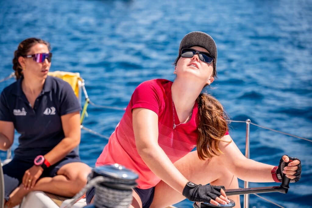 Two women trim the sails at the winch during skipper training