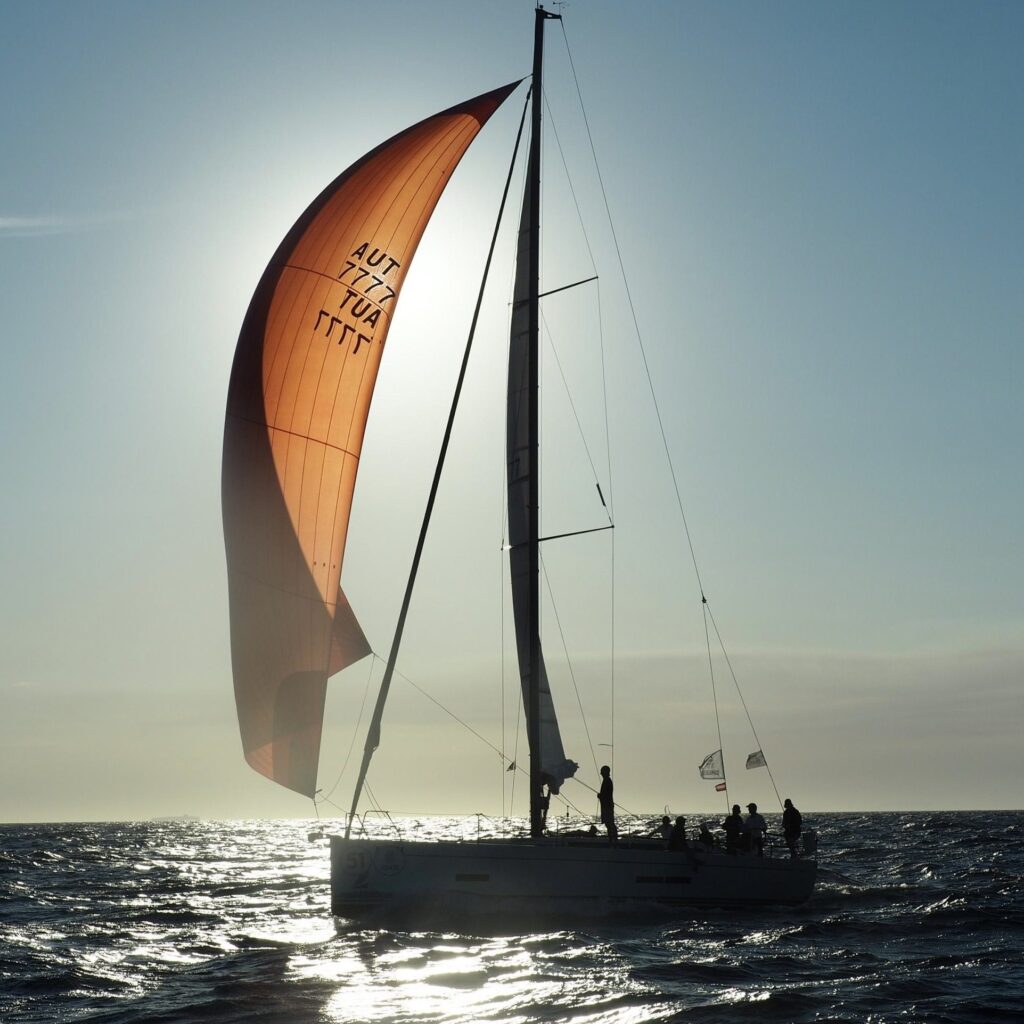 Solaris 44.1 TRINITY+ with orange gennaker backlit on the Adriatic
