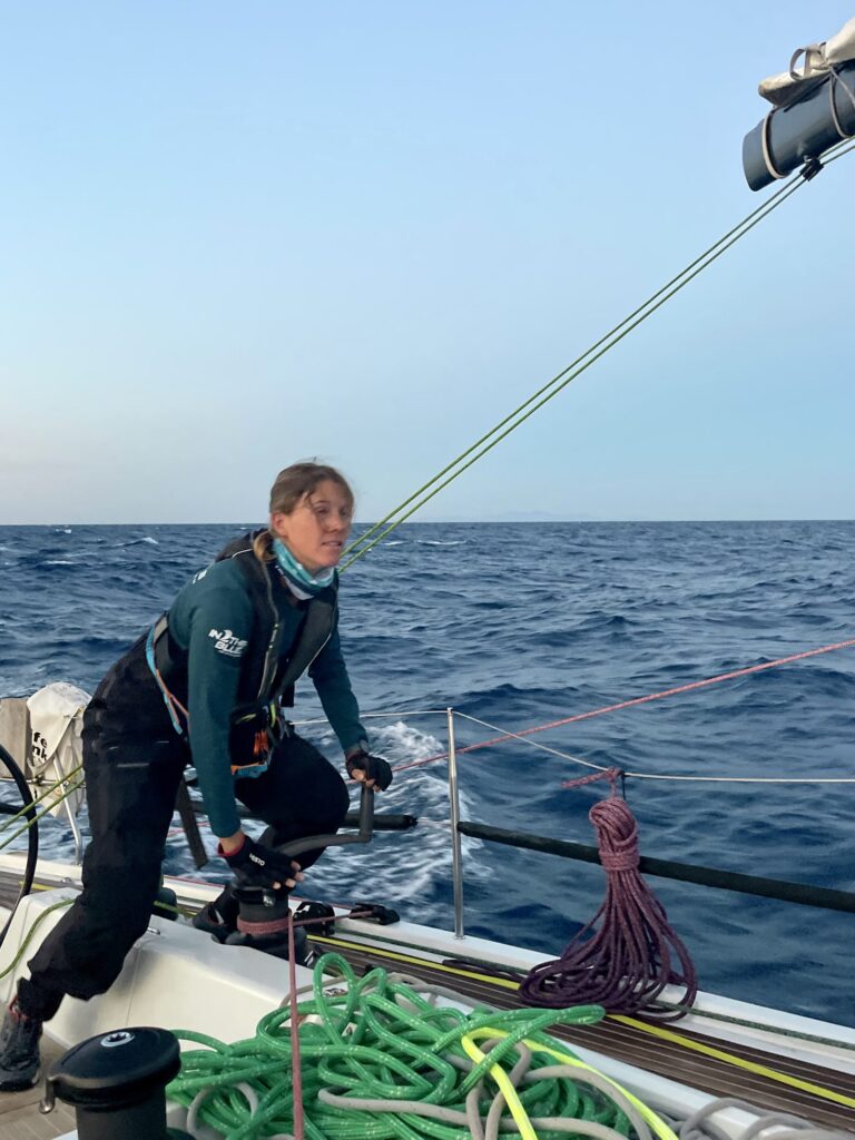 Sailor working the winch on the side deck of TRINITY+