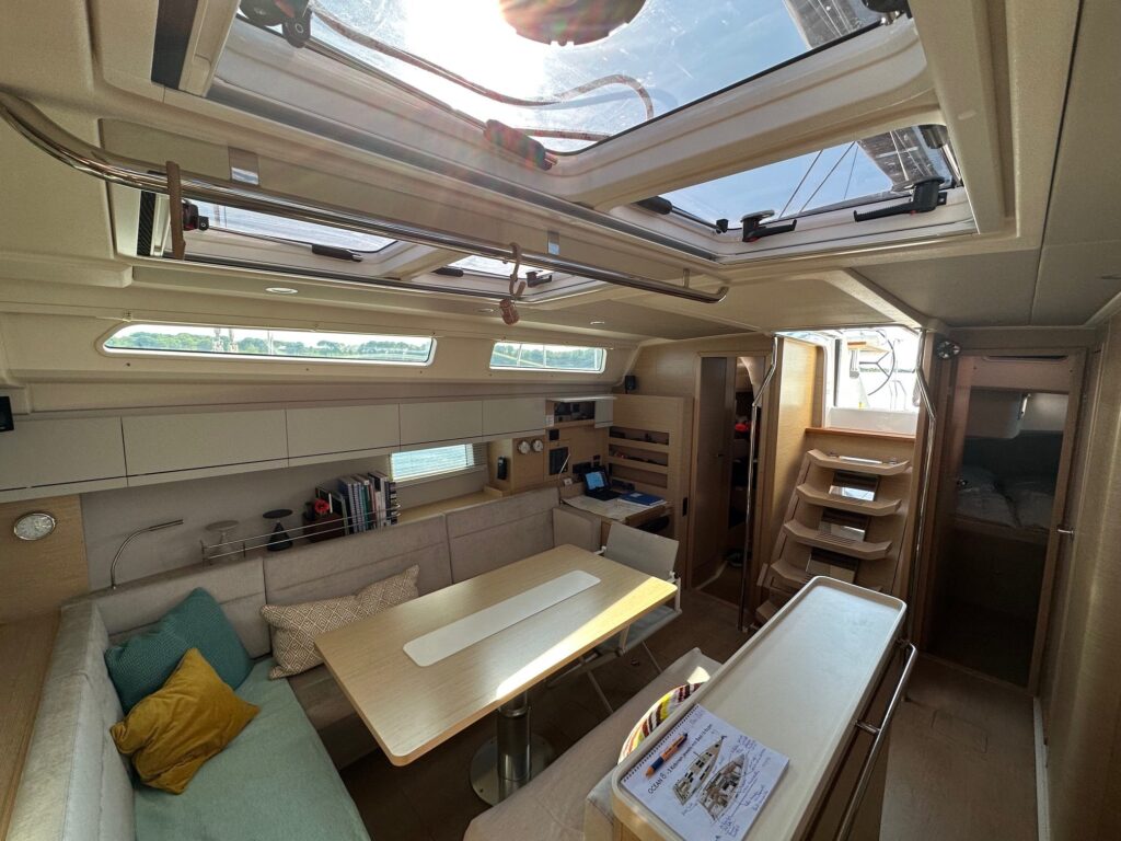 Bright saloon of a sailing yacht with seating area and overhead hatches